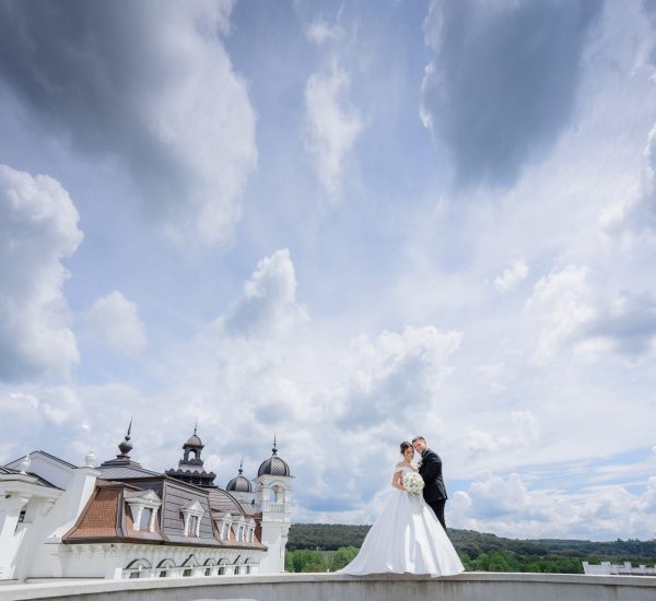 Beautiful wedding couple is standing near the church with beautiful cloudy sky